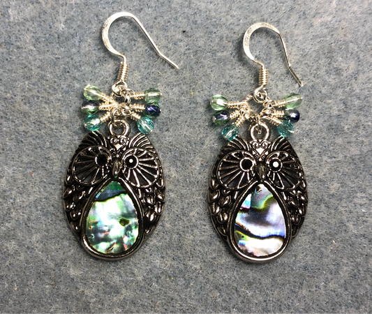 Silver and abalone owl charm earrings adorned with small dangling light green, aqua, and violet Czech glass beads.