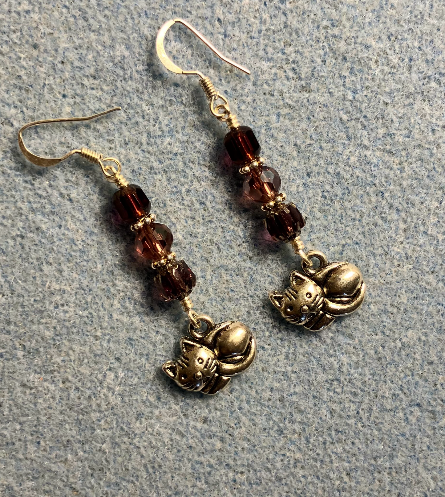 Silver sleeping cat charm earrings adorned with purple Czech glass beads.