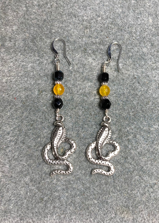 Long silver cobra charm earrings adorned with black and yellow Czech glass beads.