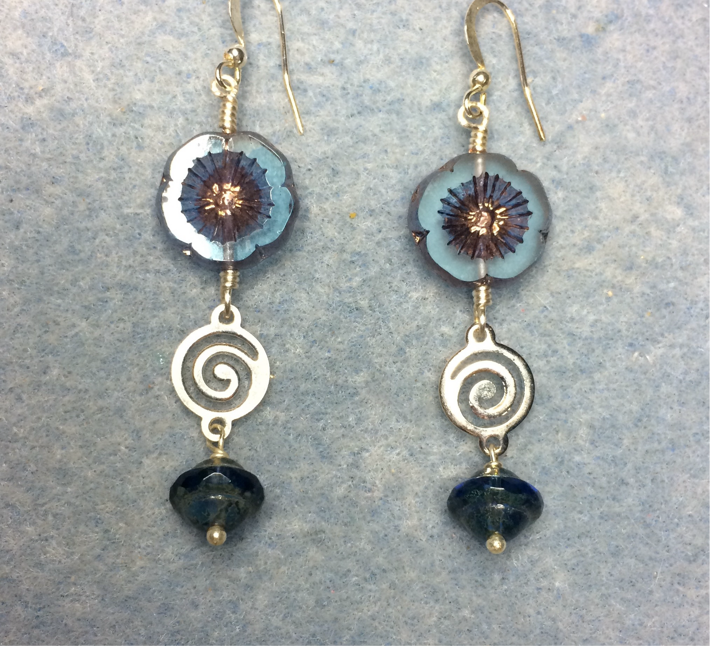 Translucent blue and copper Czech glass pansy bead earrings adorned with silver swirly connectors and blue Czech glass Saturn beads.