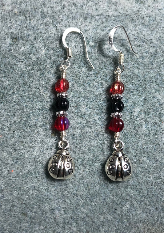 Silver ladybug charm earrings adorned with red and black Czech glass beads.