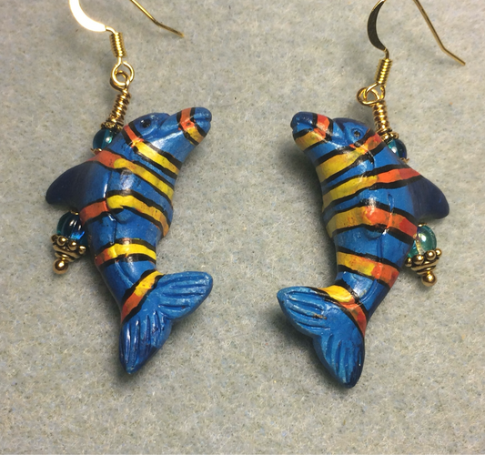 Turquoise blue, red, and yellow ceramic striped dolphin bead earrings adorned with turquoise Czech glass beads.