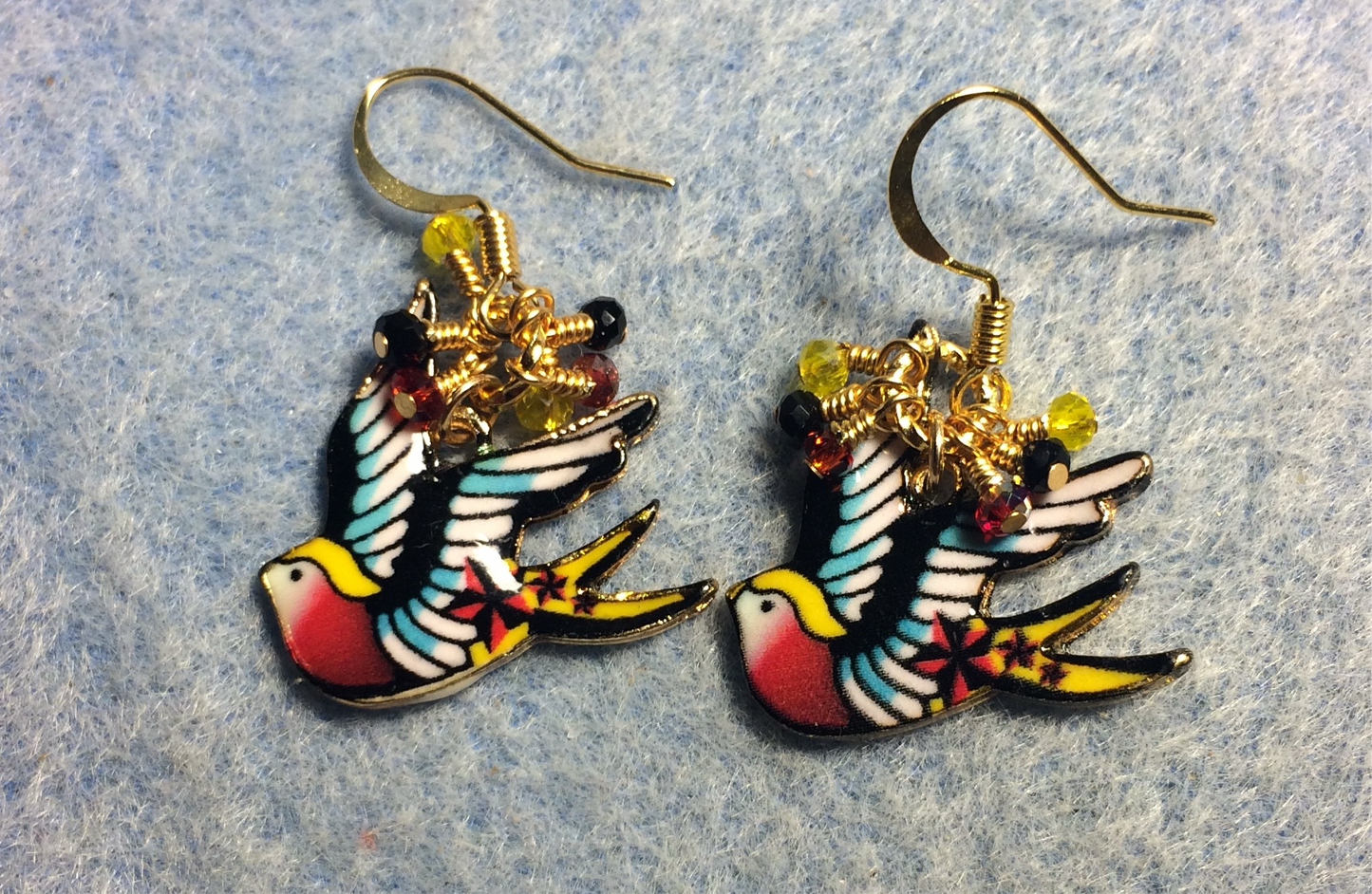 Red, black, and yellow enamel flying dove charm earrings adorned with tiny dangling red, black, and yellow Chinese crystal beads.