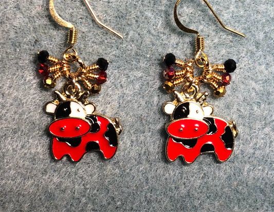 Red, black, and white enamel cow charm earrings adorned with tiny dangling red, black, and gold Chinese crystal beads.