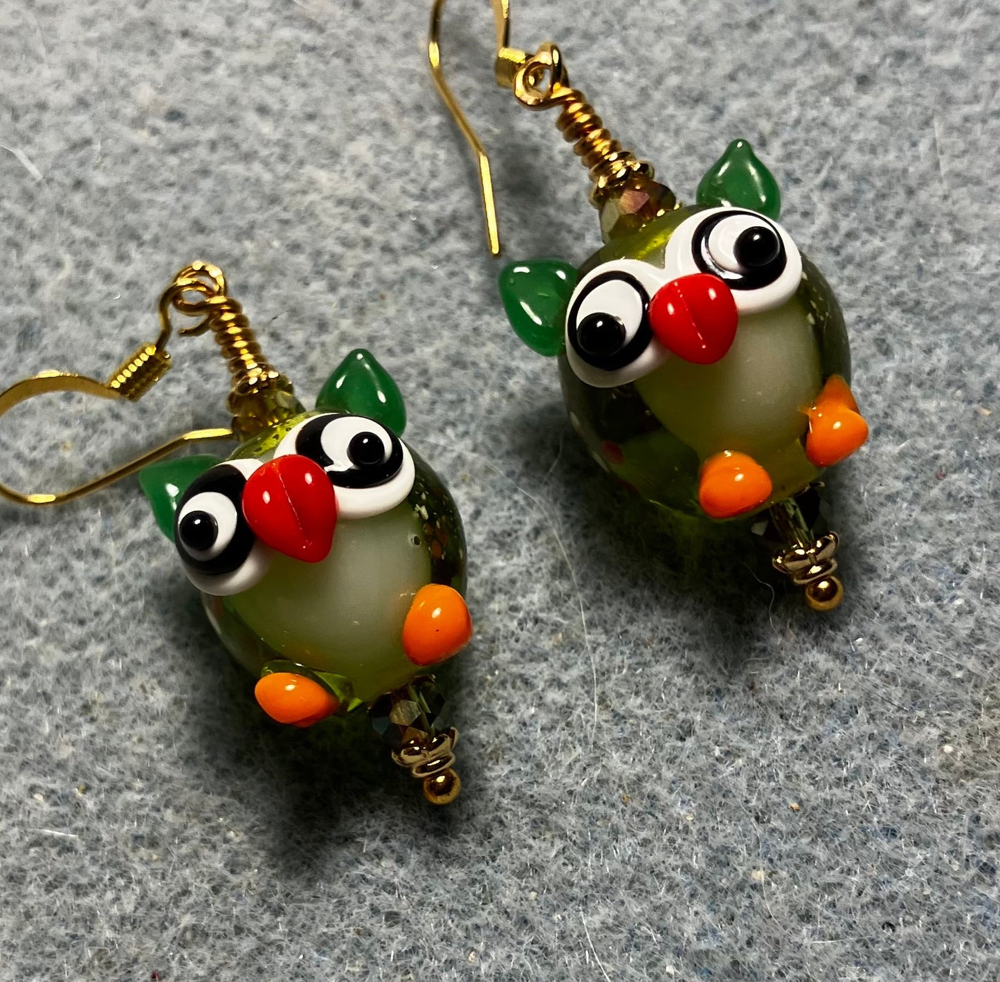 Olive green, orange, and red lamp work owl bead earrings adorned with olive green Chinese crystal beads.