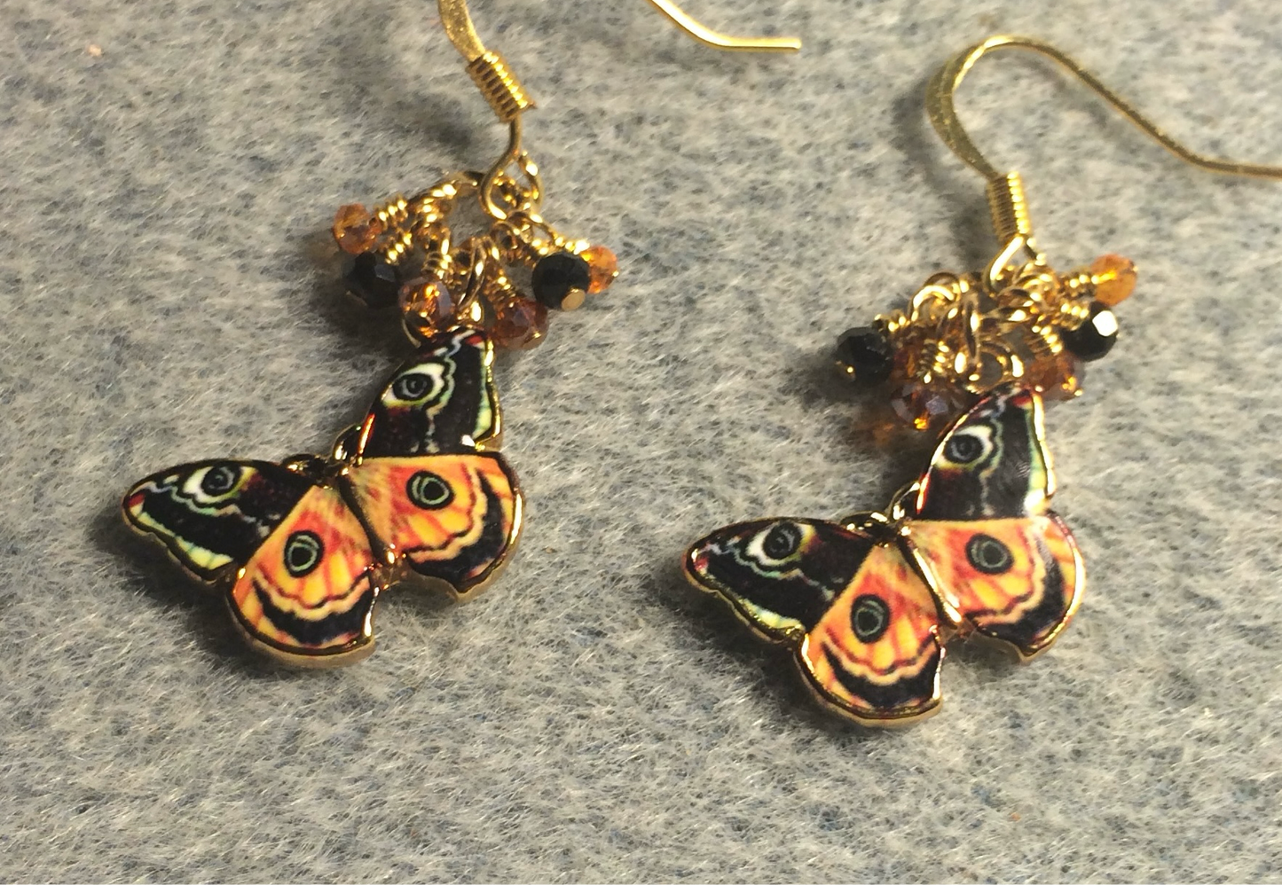 Orange and black enamel butterfly charm earrings adorned with tiny dangling orange and black Chinese crystal beads.