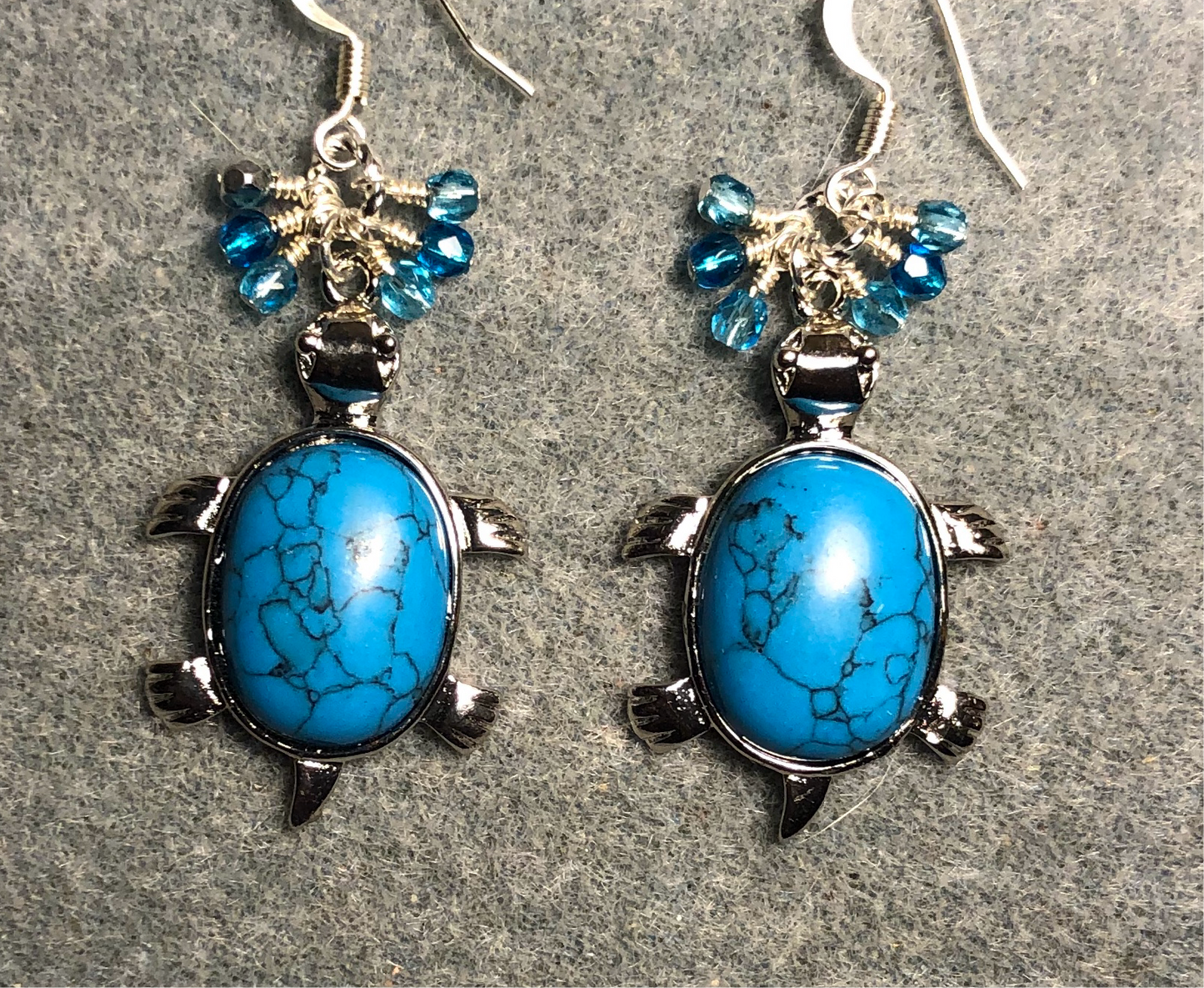 Large silver and turquoise howlite gemstone turtle charm earrings adorned with small dangling turquoise and aqua Czech glass beads.