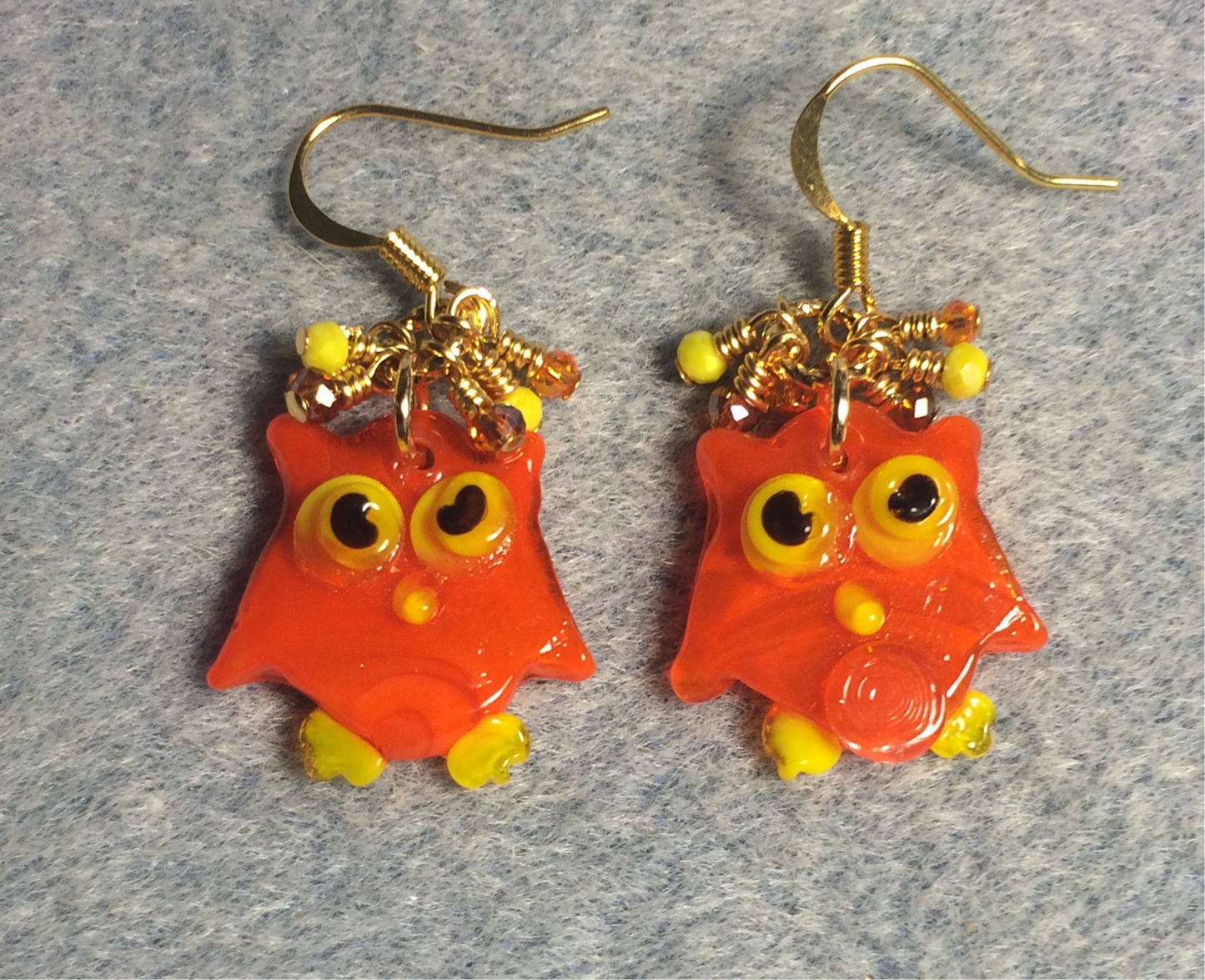 Flat orange and yellow lamp work owl charm earrings adorned with tiny dangling orange and yellow Chinese crystal beads.
