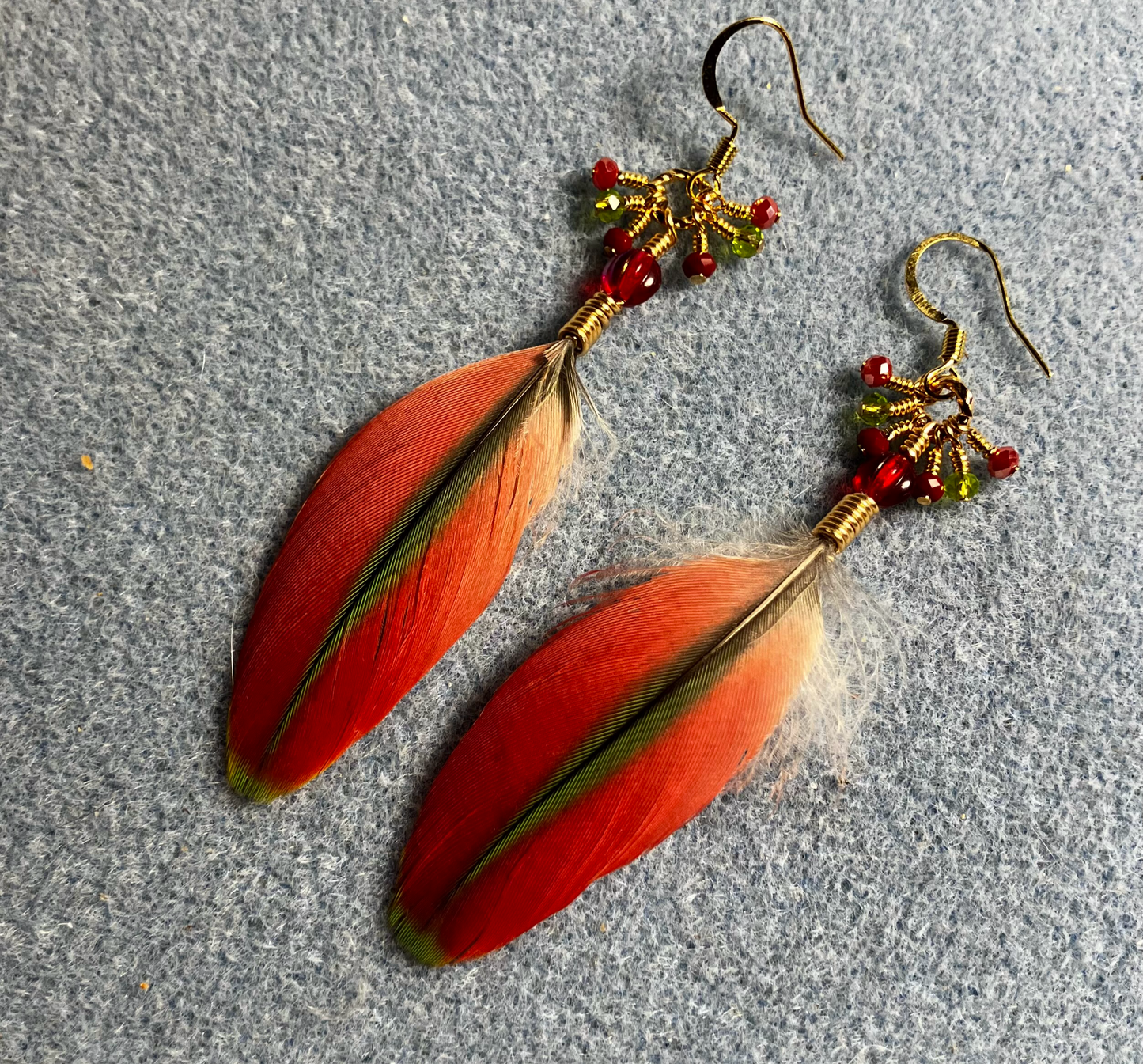 Small red and olive green Pionus feather earrings adorned with red Czech glass beads and tiny dangling red and olive green Chinese crystal beads.