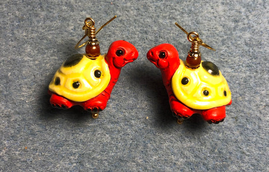 Large red orange and yellow ceramic turtle bead earrings adorned with red orange Czech glass beads.