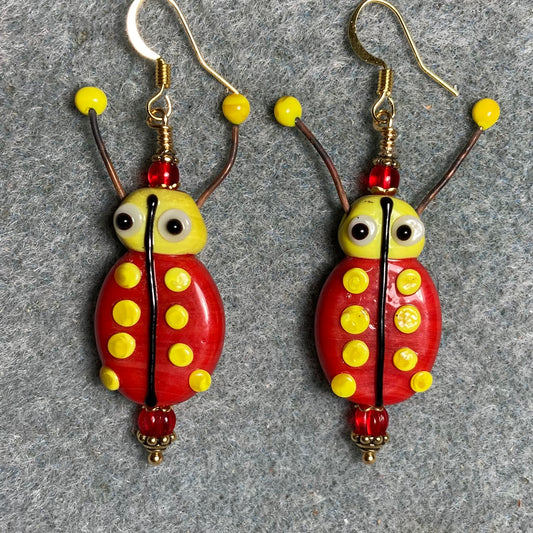 Red and yellow lamp work beetle bead earrings adorned with red Czech glass beads.