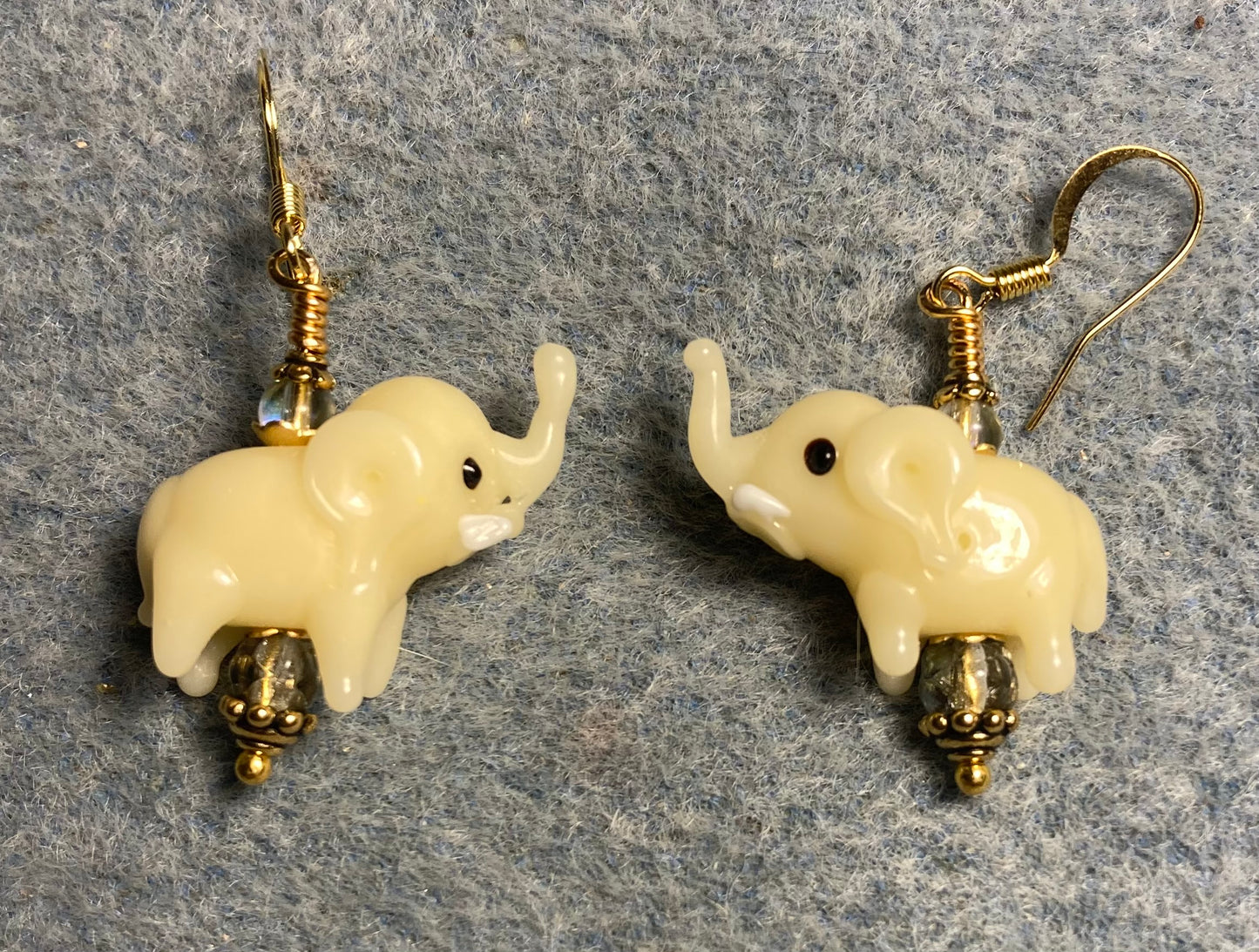 Opaque pale yellow lamp work elephant bead earrings adorned with light yellow Czech glass beads.