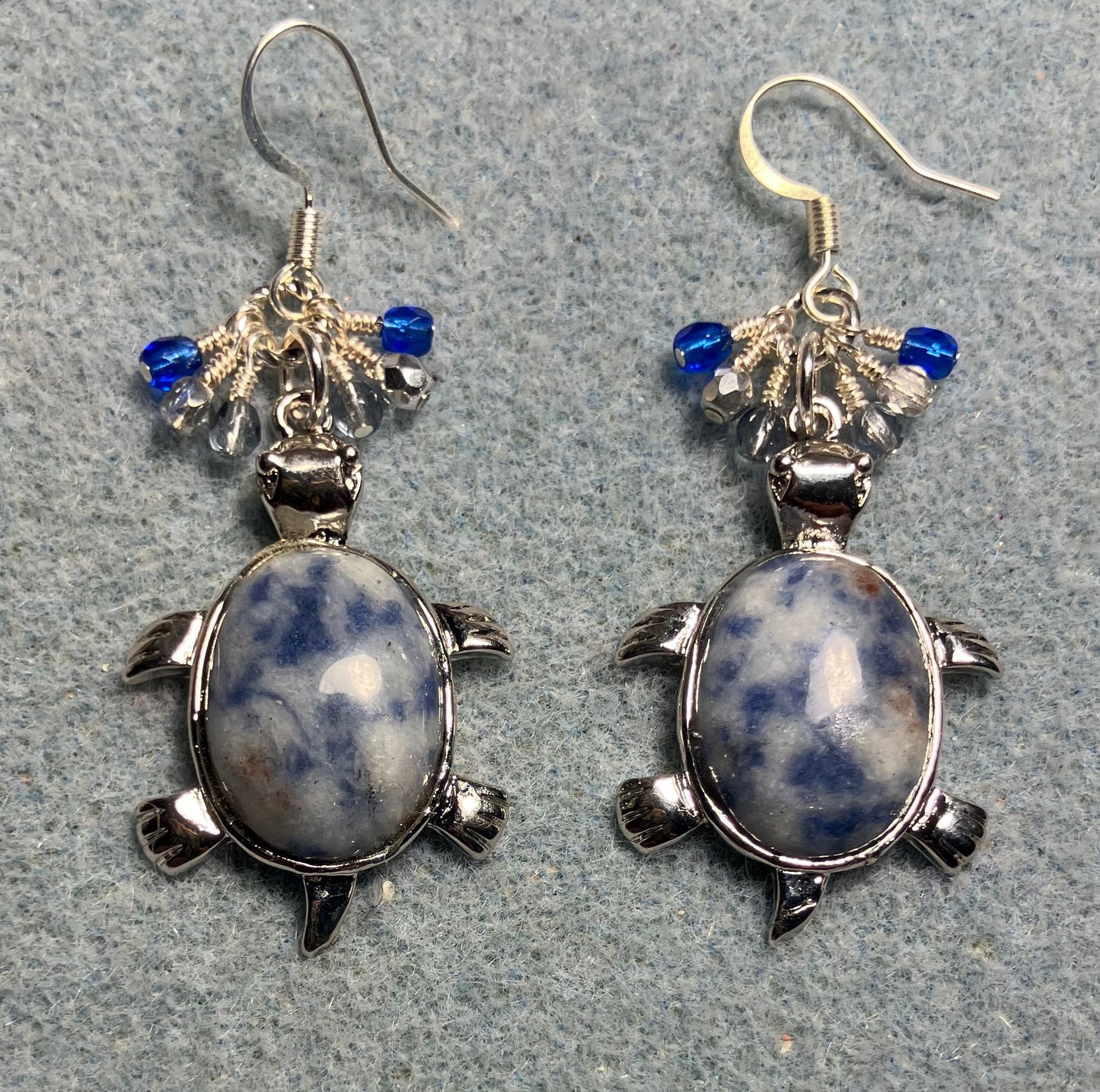 Large silver and blue sodalite gemstone turtle charm earrings adorned with small dangling dark blue, light blue, and silver Czech glass beads.