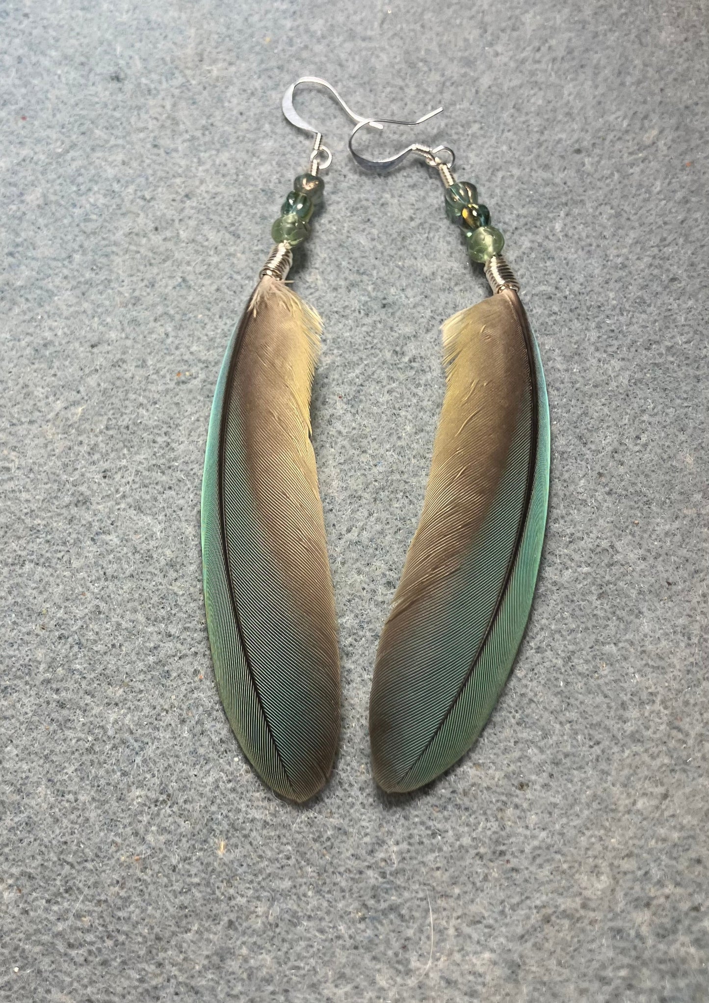 Small pointed green gray red-fronted macaw feather earrings adorned with small green gray Czech glass beads.