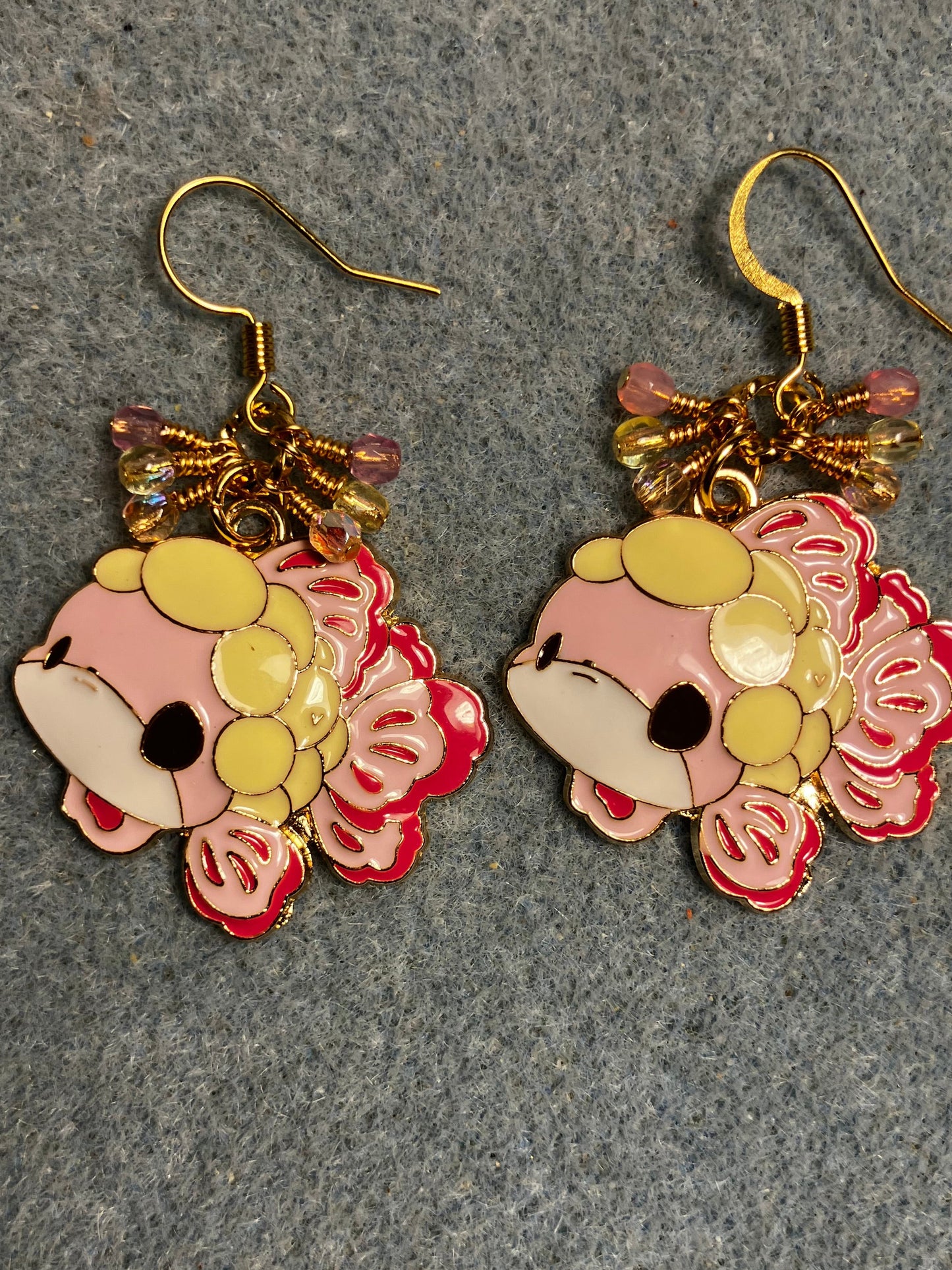 Large pink, yellow, and black enamel fish charm earrings adorned with small dangling pink and yellow Czech glass beads.