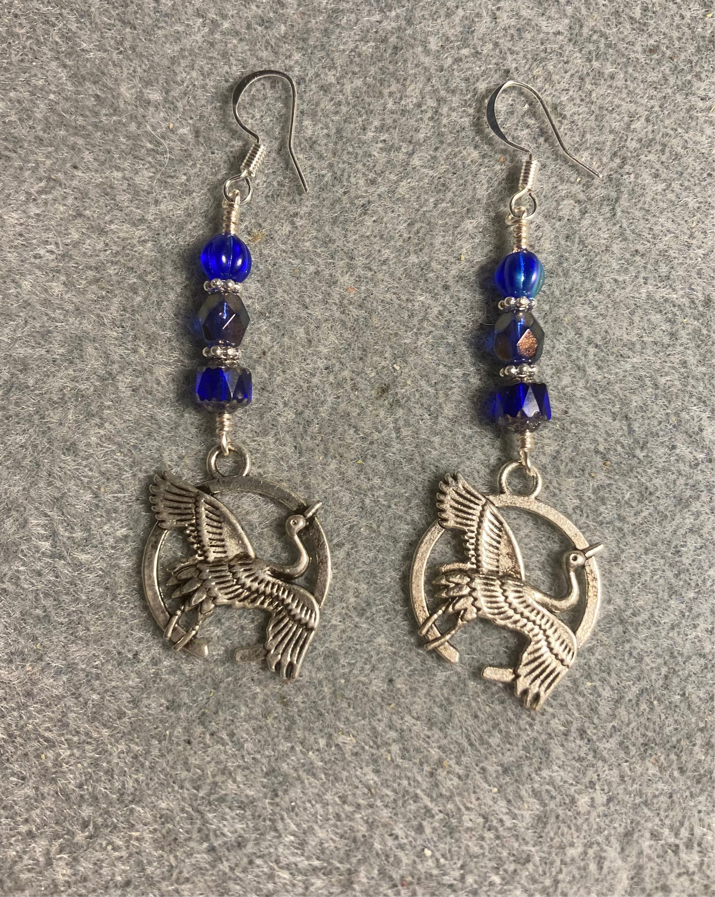 Silver flying crane charm earrings adorned with dark blue Czech glass beads.