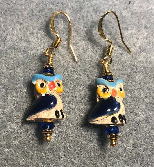 Small tan, turquoise, yellow, and dark blue ceramic owl bead earrings adorned with dark blue Chinese crystal beads.
