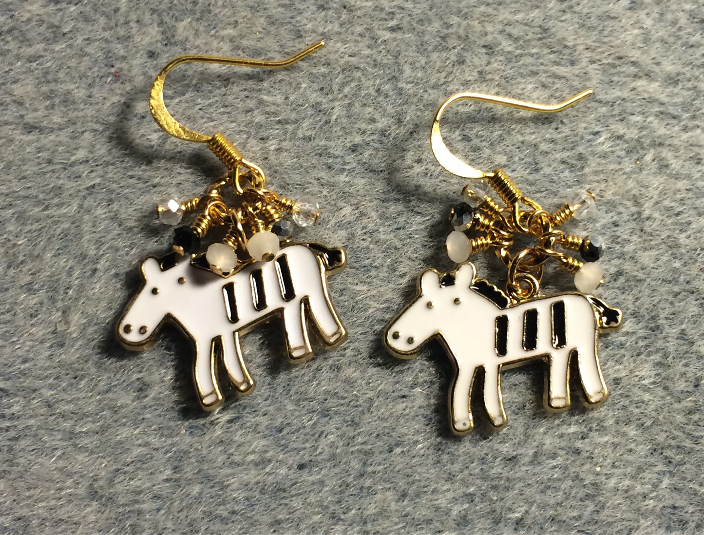 White and black enamel horse charm earrings adorned with tiny dangling white, black, and clear Chinese crystal beads.