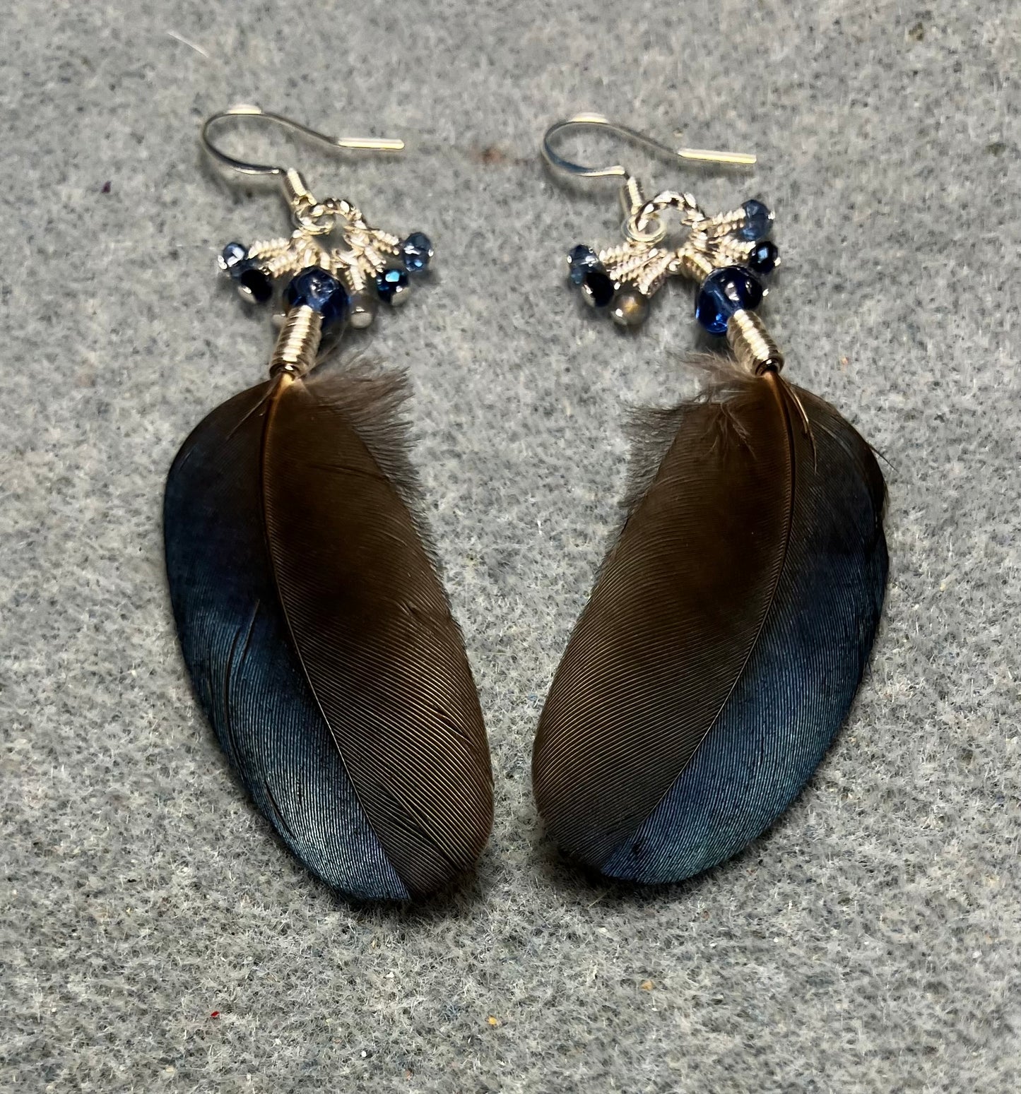 Small blue magpie feather earrings adorned with small blue Czech glass beads and tiny dangling blue Chinese crystal beads.