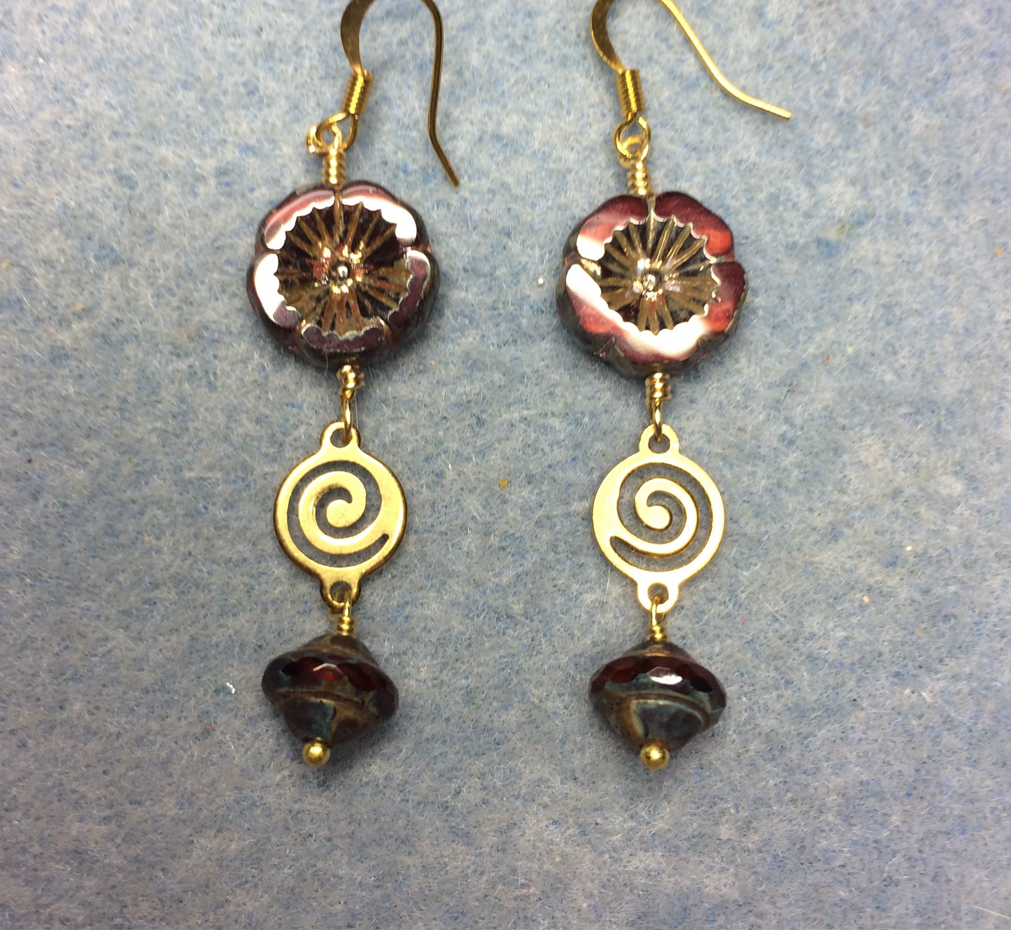 Brick red Czech glass pansy bead earrings adorned with gold swirly connectors and red Czech glass Saturn beads.