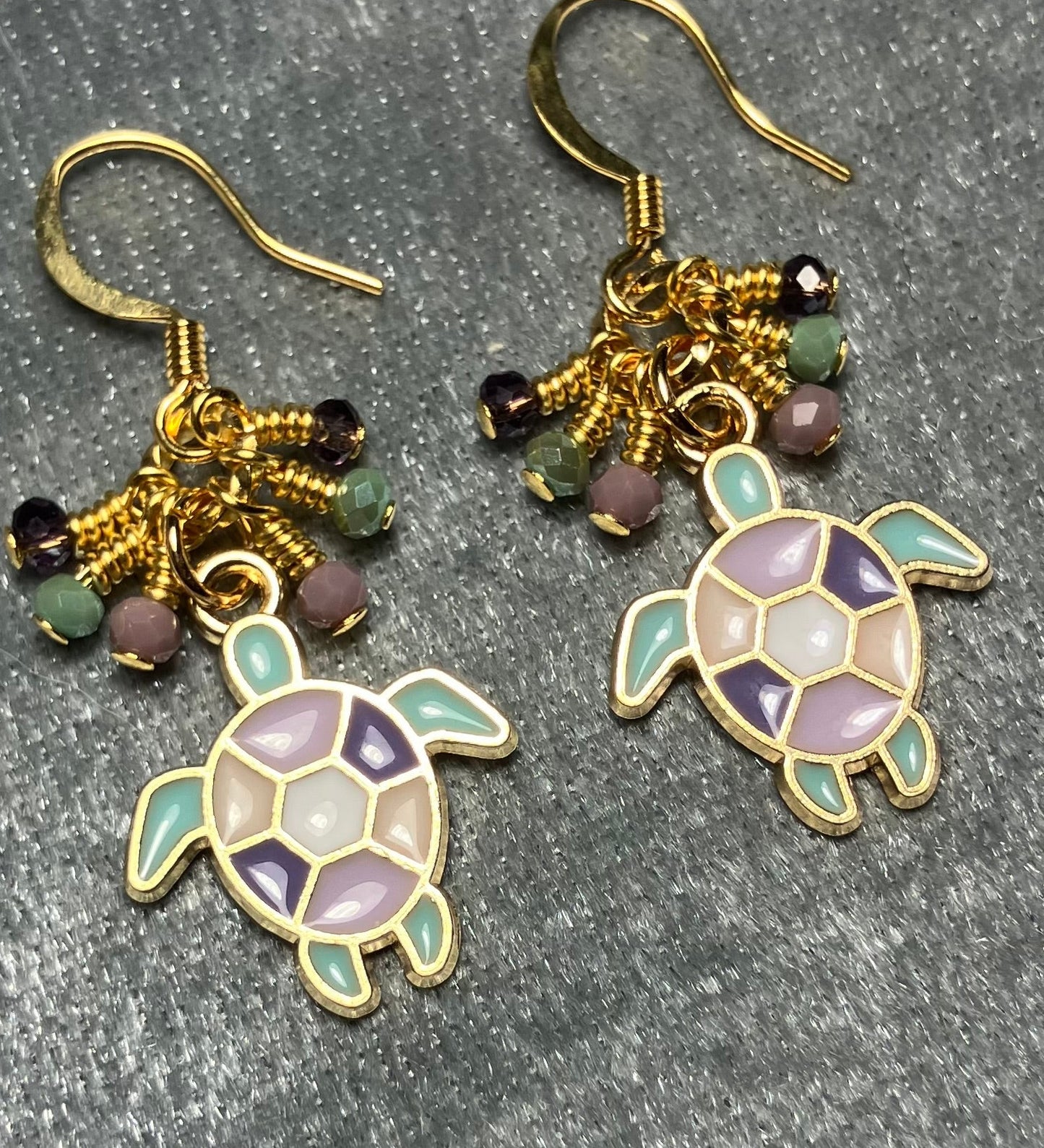 Purple, light green, and violet enamel sea turtle charm earrings adorned with tiny dangling purple, light green, and violet Chinese crystal beads.