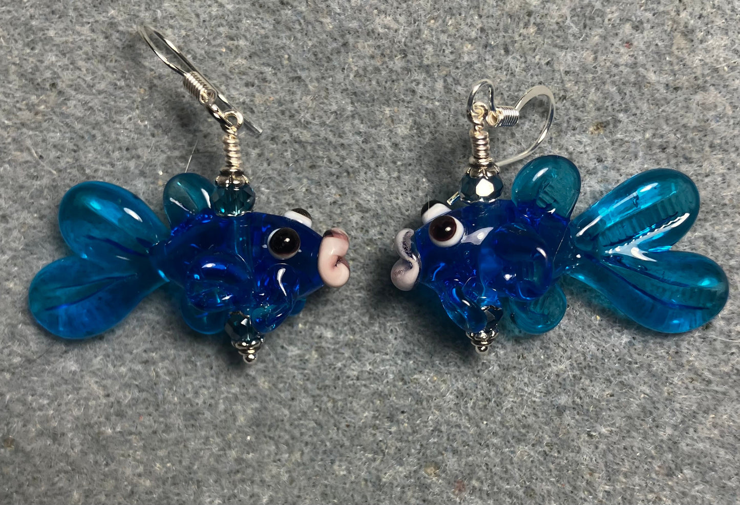 Translucent turquoise blue lamp work fish bead earrings adorned with turquoise blue Chinese crystal beads.
