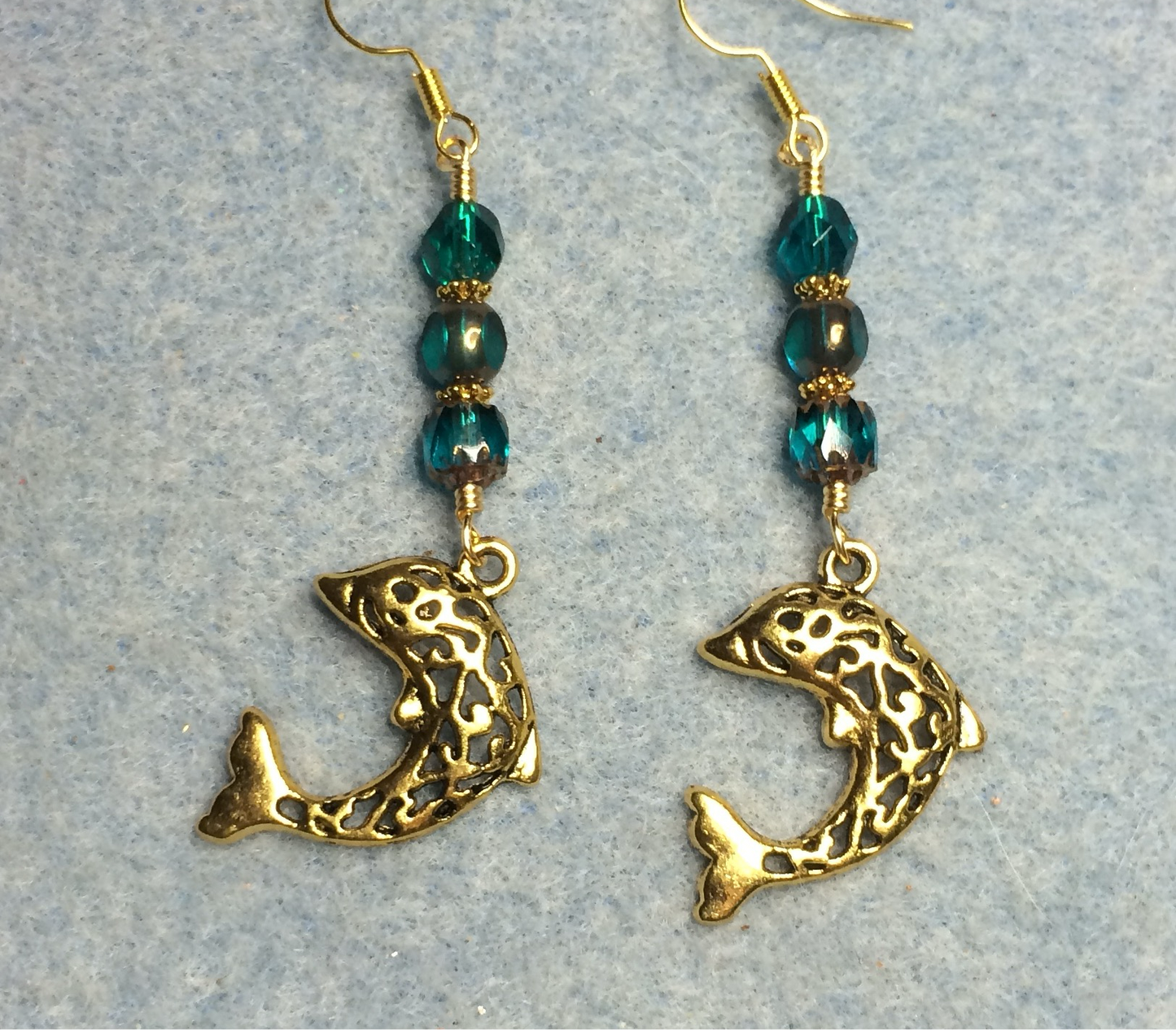 Large fancy gold dolphin charm earrings adorned with teal Czech glass beads