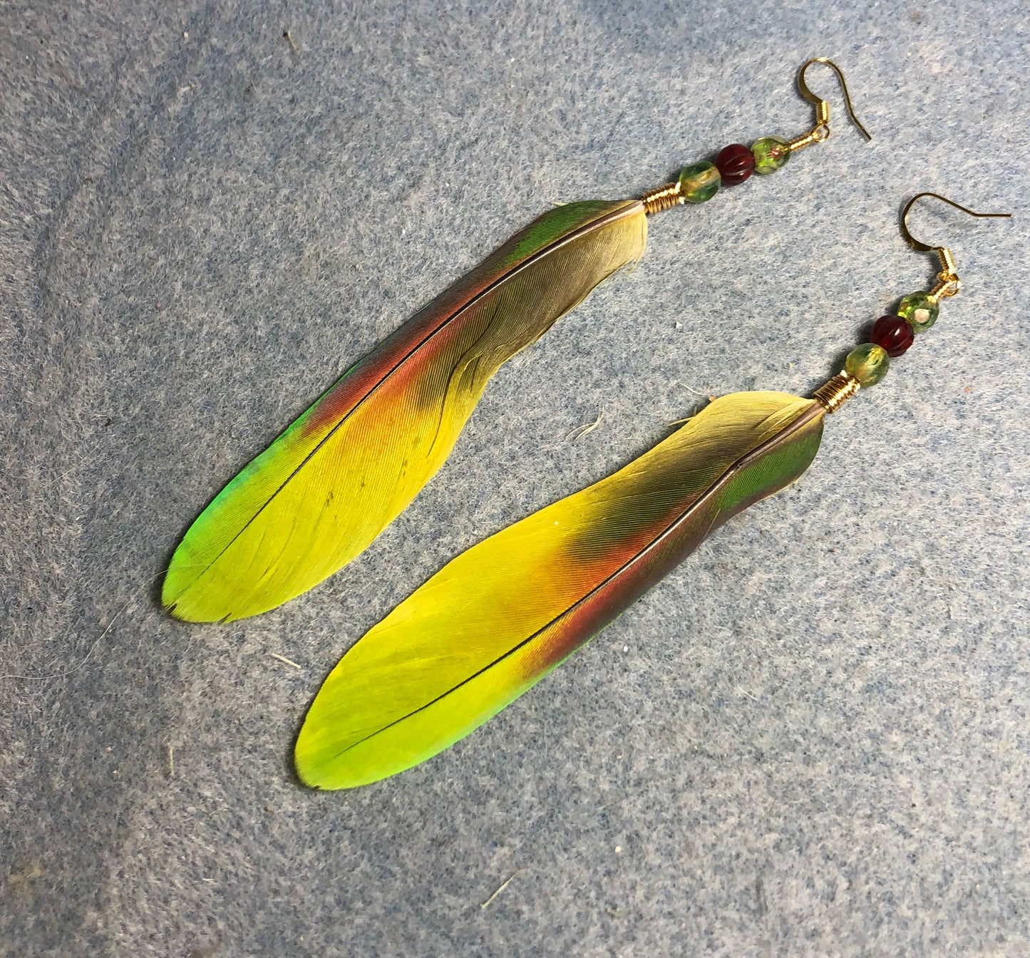 Lilac crowned Amazon parrot tail feather earrings adorned with green and red Czech glass beads.