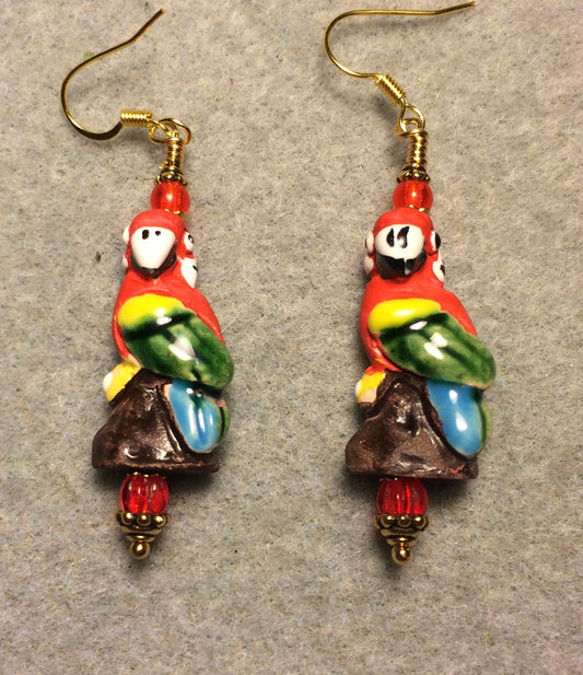 Large red, green, yellow, and blue ceramic parrot bead earrings adorned with red Czech glass beads.