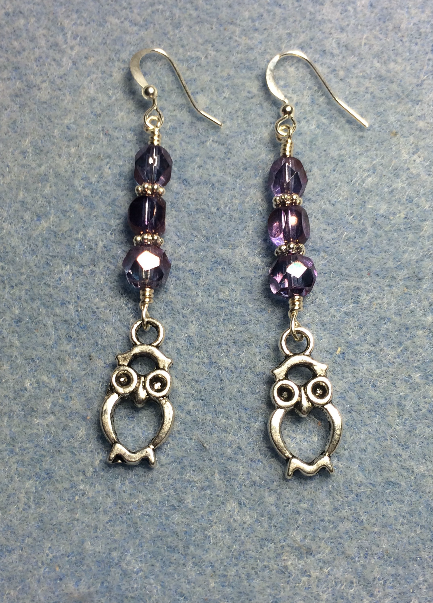 Silver owl charm earrings adorned with purple Czech glass beads.