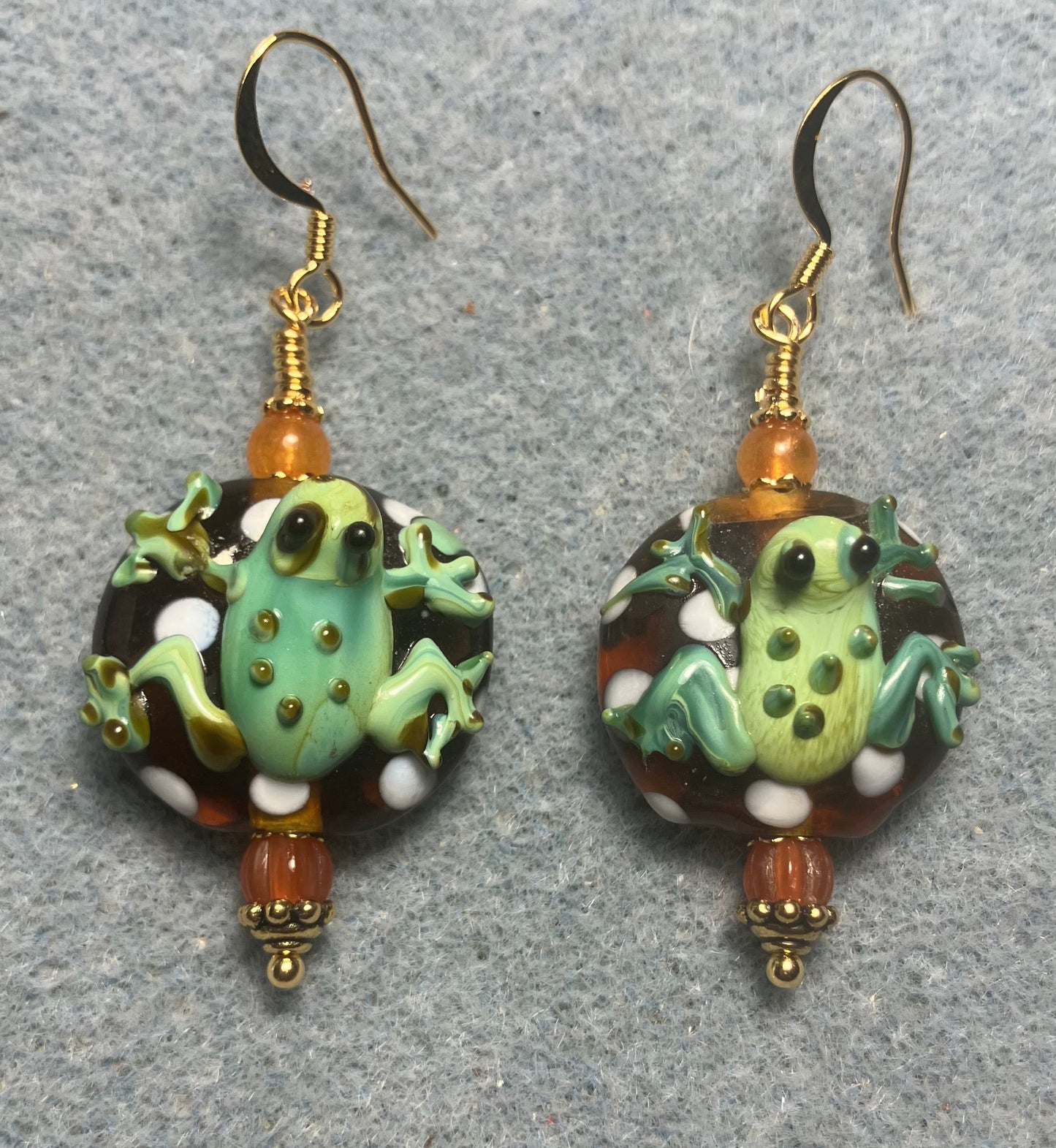 Orange and green lamp work frog bead earrings adorned with orange Czech glass beads.
