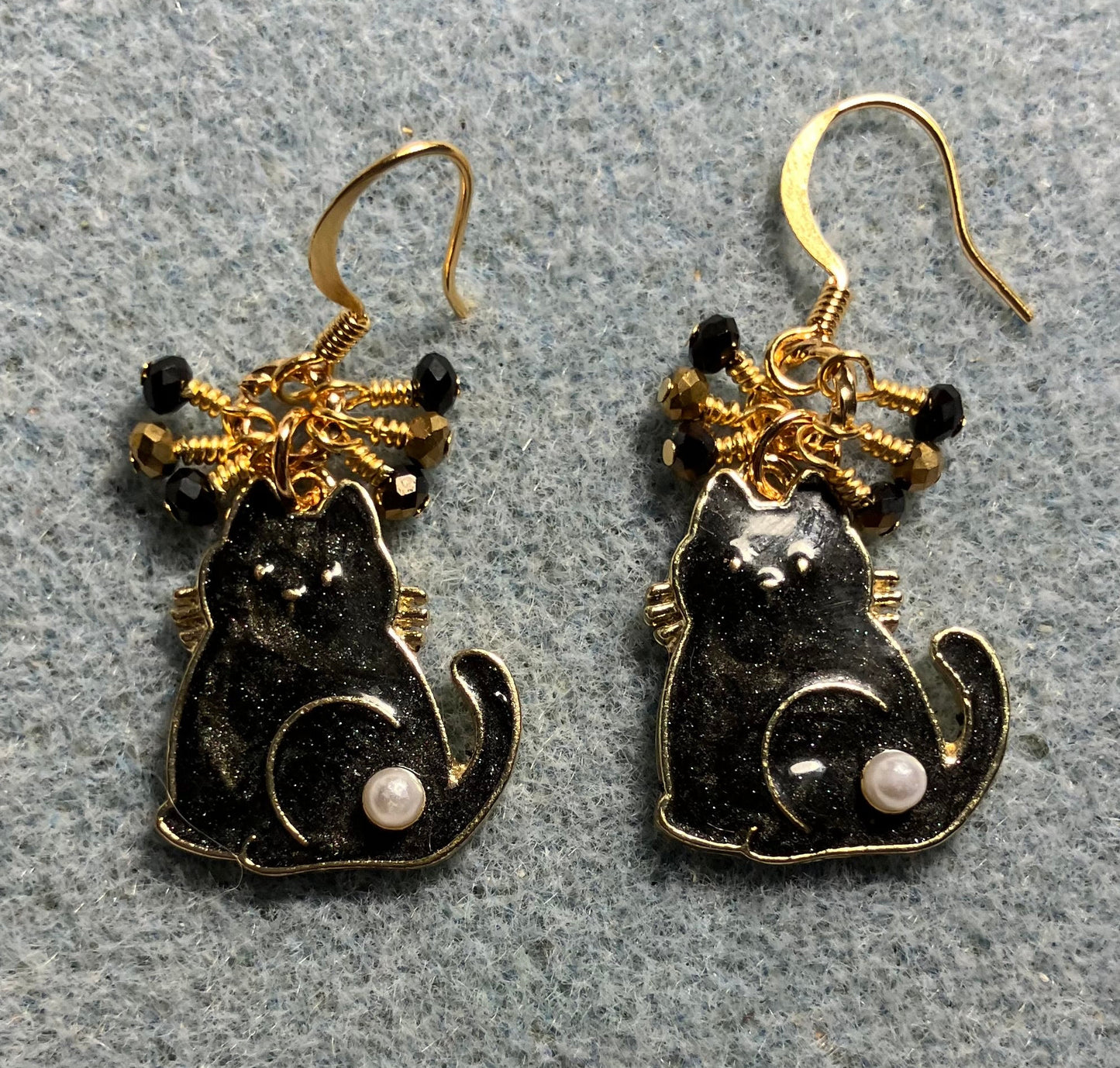 Black and gold enamel and pearl cat charm earrings adorned with tiny dangling black and gold Chinese crystal beads.