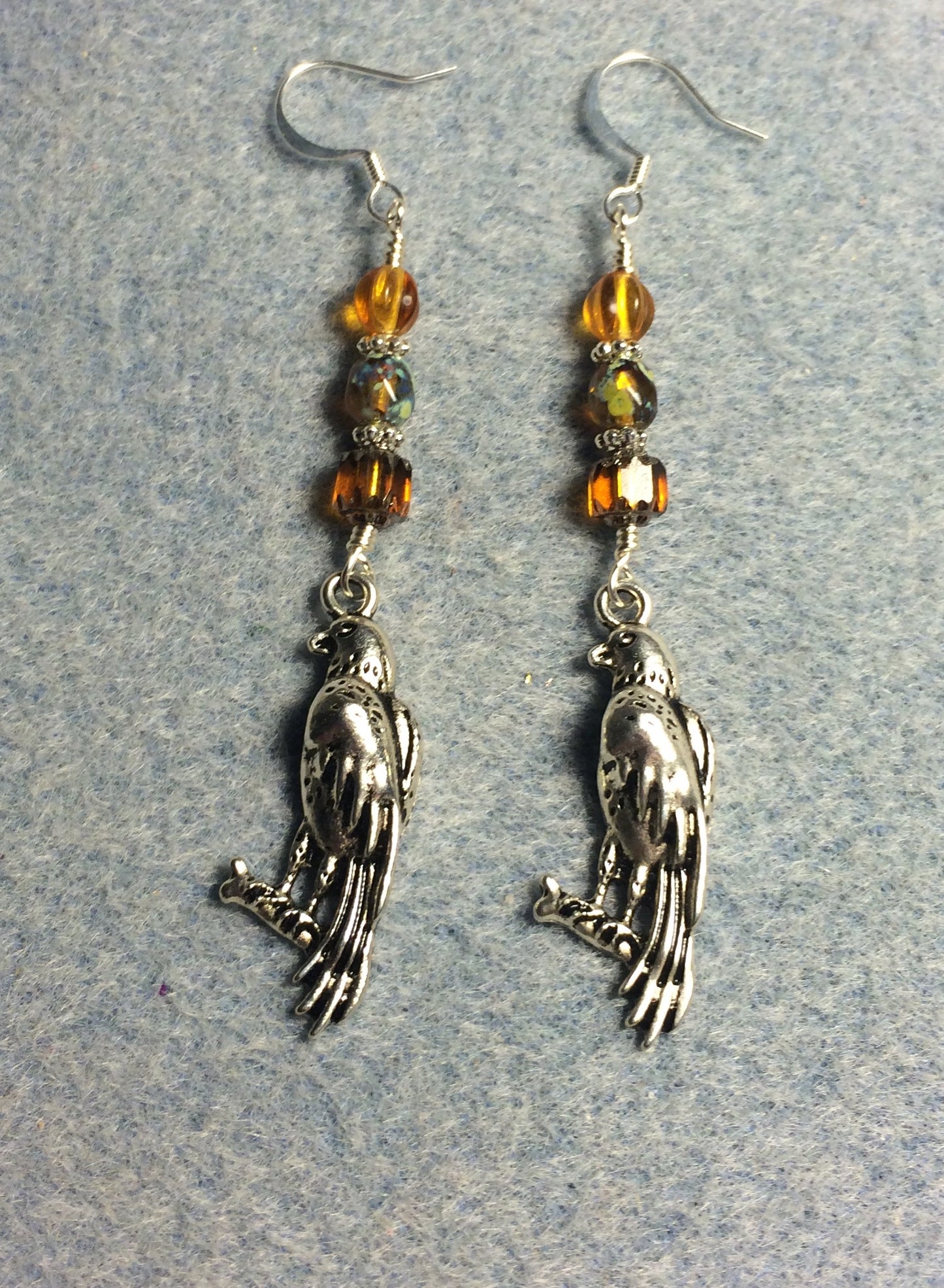 Long silver falcon charm earrings adorned with amber Czech glass beads