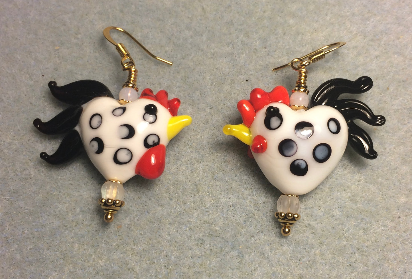 White with black spots heart shaped lamp work rooster bead earrings adorned with clear Czech glass beads.