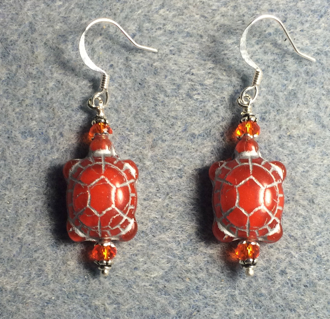 Red orange (with silver inlay) Czech glass turtle bead earrings adorned with orange Chinese crystal beads.