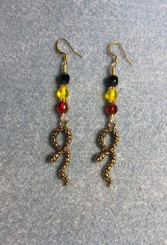 Gold snake charm earrings adorned with red, yellow, and black Czech glass beads
