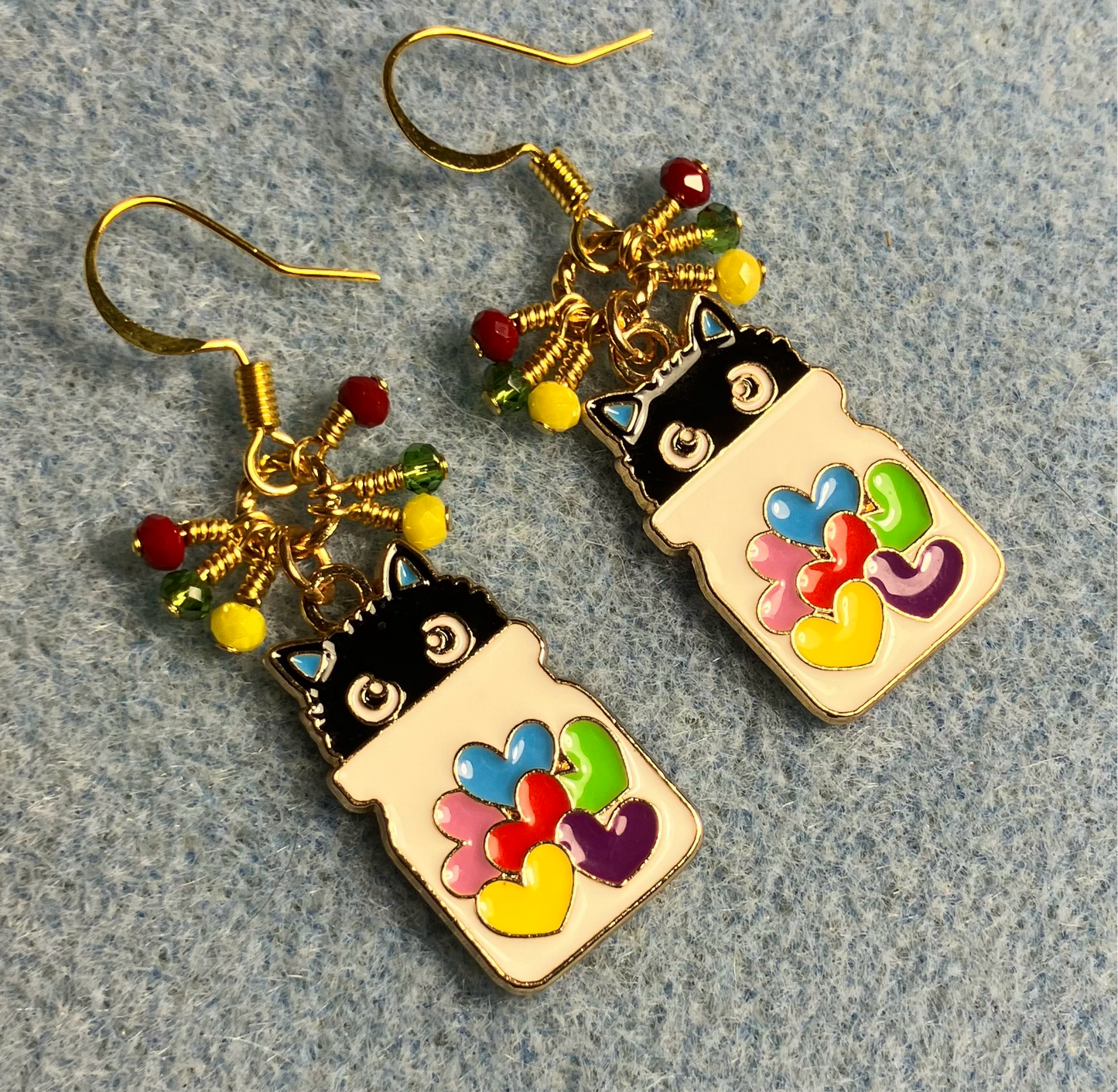 White, black, red, yellow, and green enamel cat charm earrings adorned with tiny dangling red, yellow, and green Chinese crystal beads.