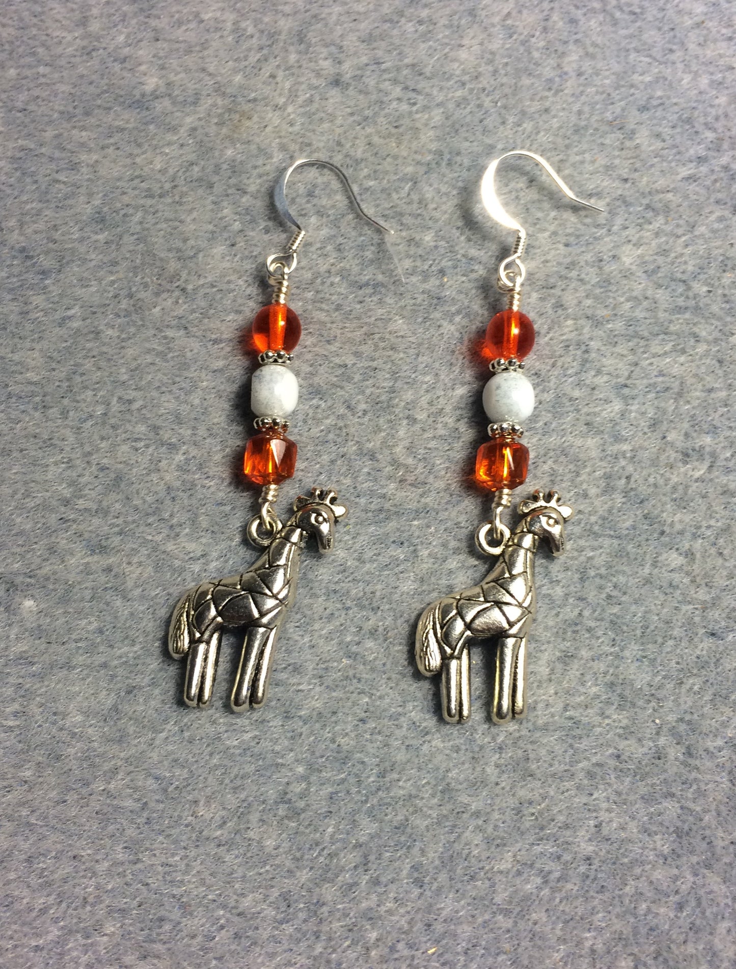 Silver giraffe charm earrings adorned with orange and white Czech glass beads