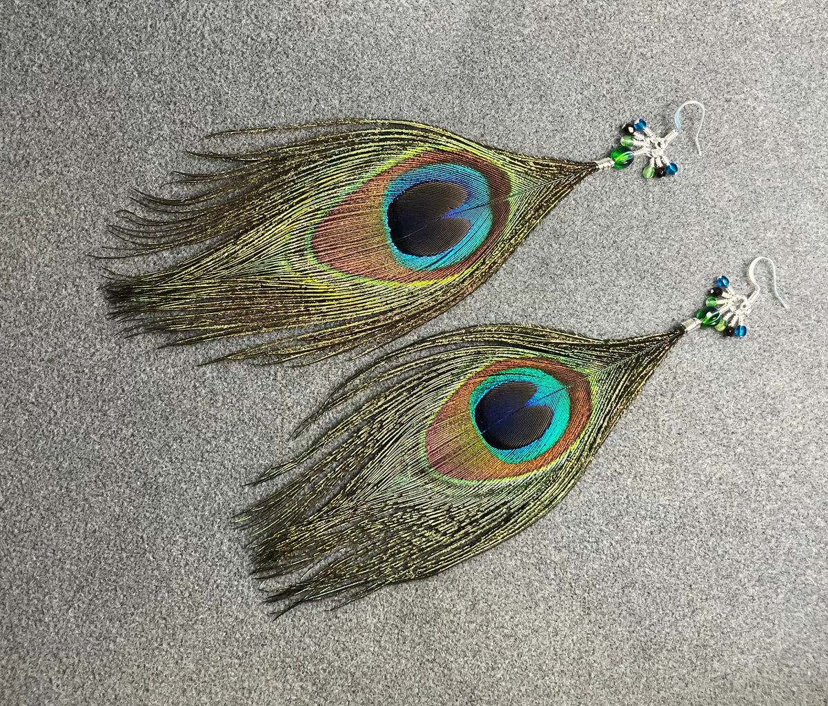 Peacock eye feather earrings adorned with small dangling green, brown, and teal Czech glass beads.