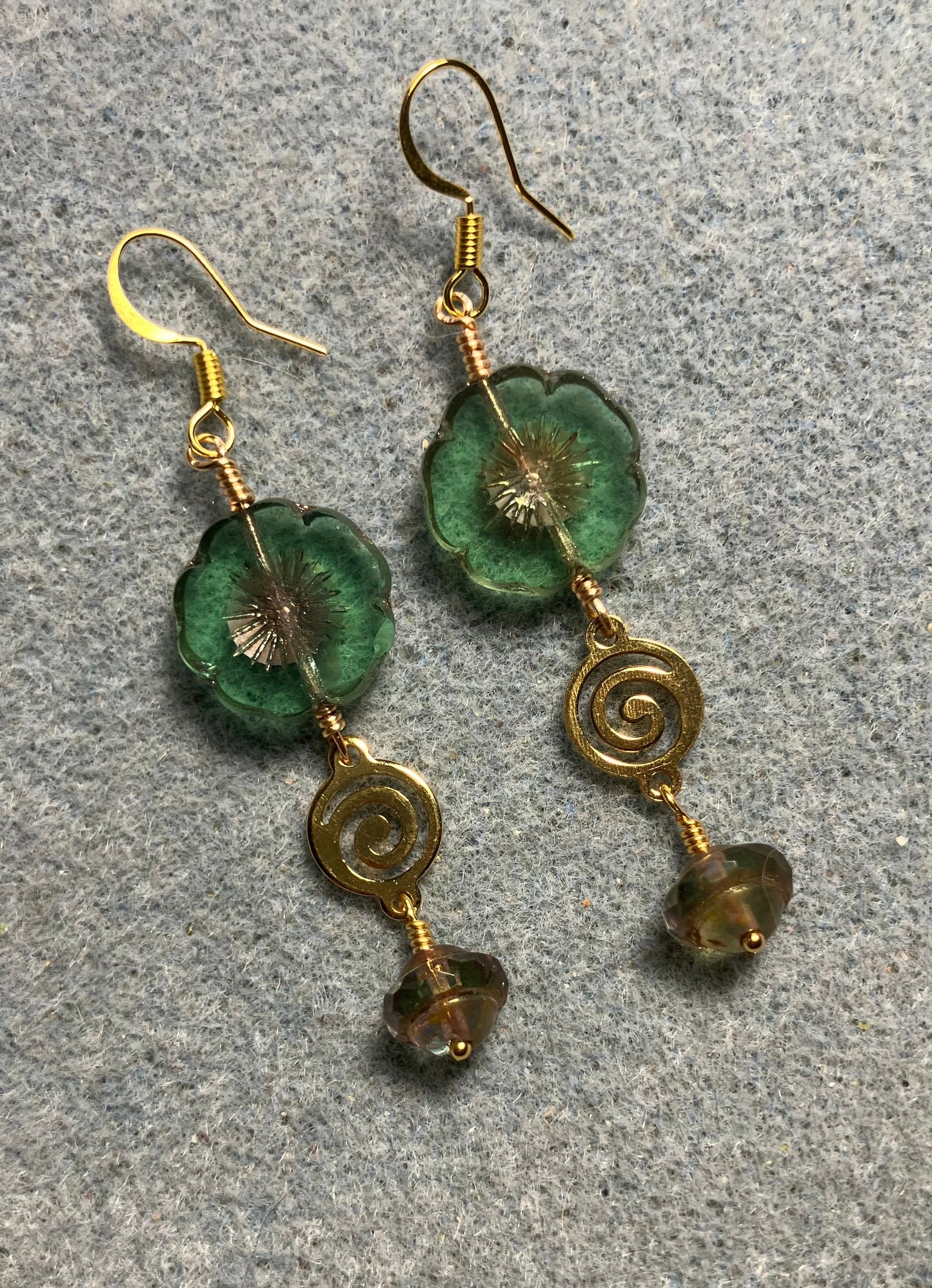 Green and gold Czech glass pansy bead earrings adorned with gold swirly connectors and green and gold Czech glass Saturn beads.