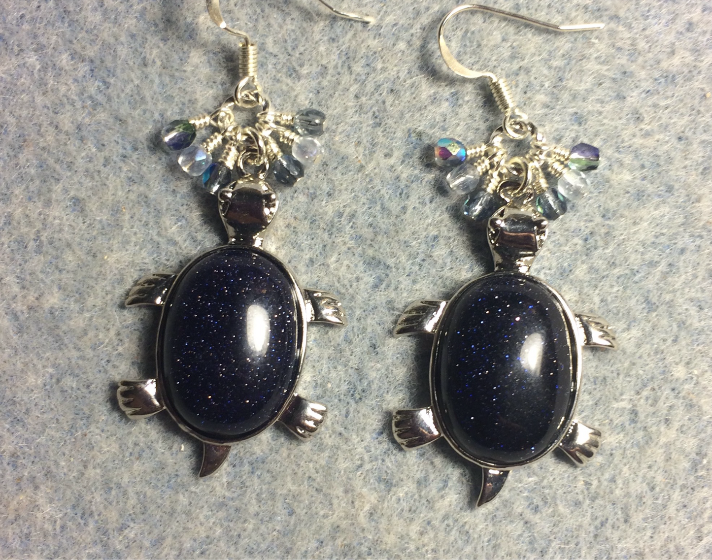 Large silver and blue goldstone gemstone turtle charm earrings adorned with small dangling blue and silver Czech glass beads.