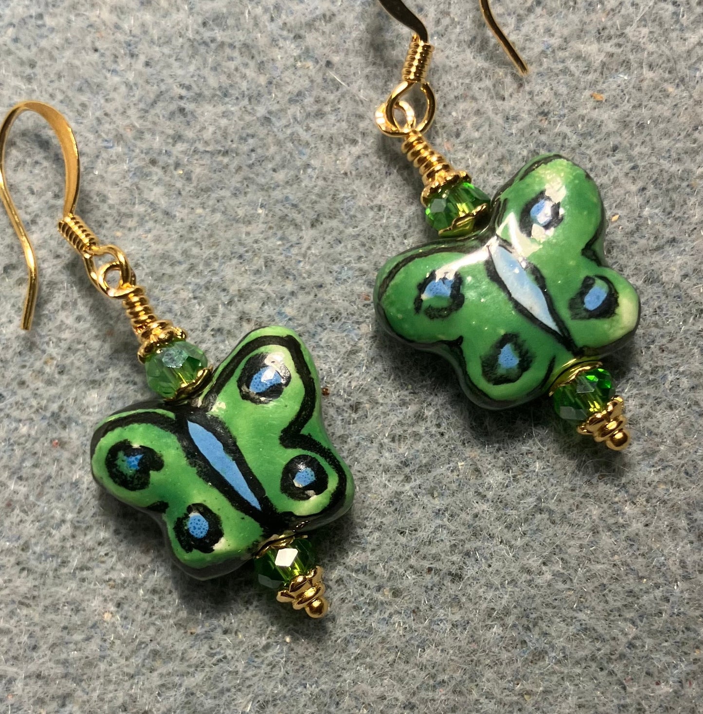Green, black, and light blue ceramic butterfly bead earrings adorned with green Chinese crystal beads.