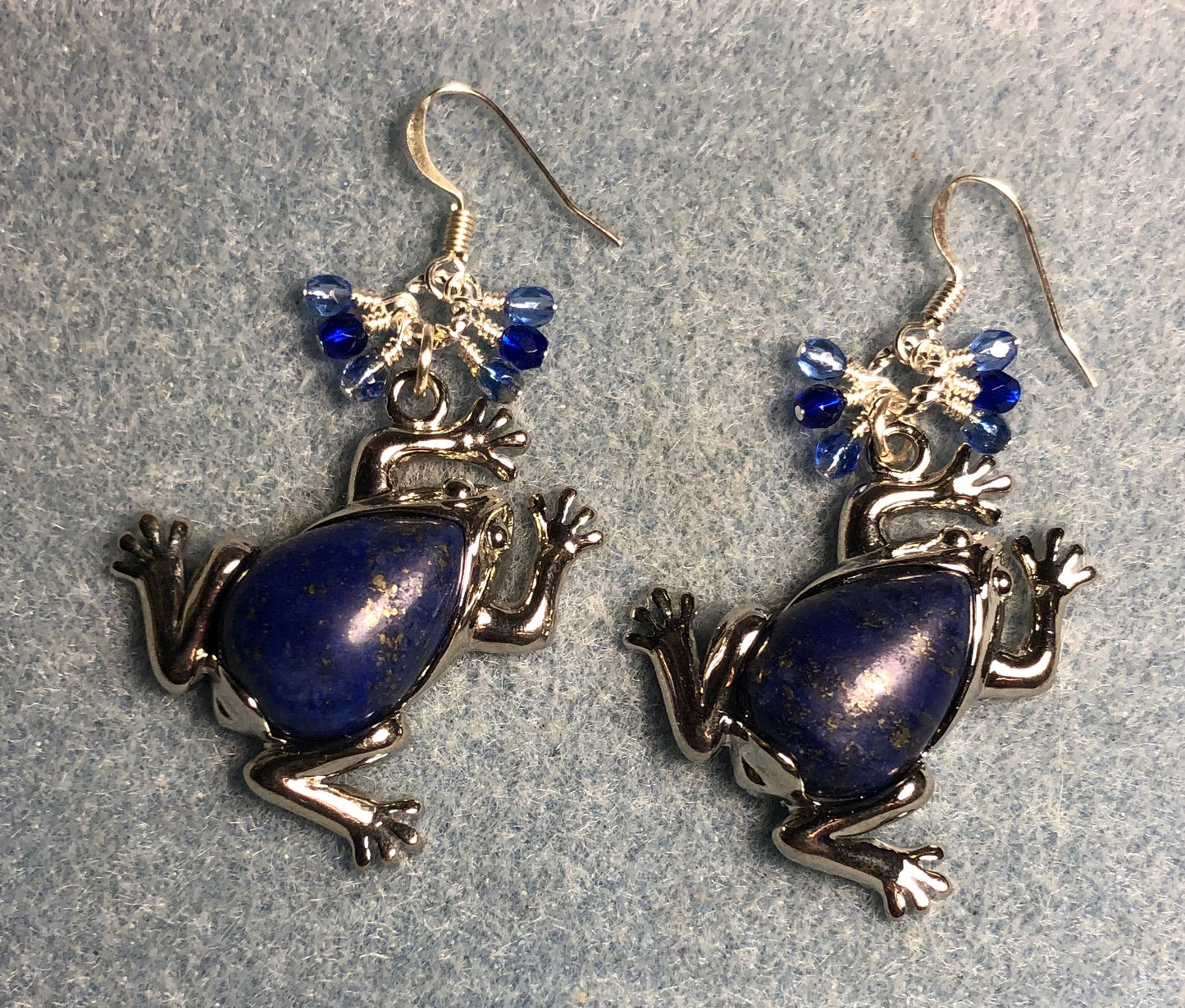 Large silver and blue lapis lazuli gemstone frog charm earrings adorned with small dangling blue Czech glass beads.