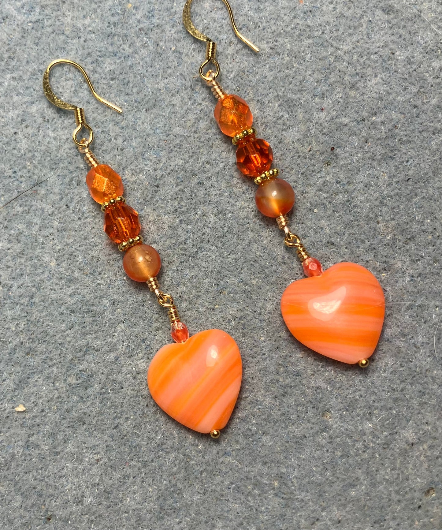 Opaque striped orange Czech glass heart bead earrings adorned with orange Czech glass beads.