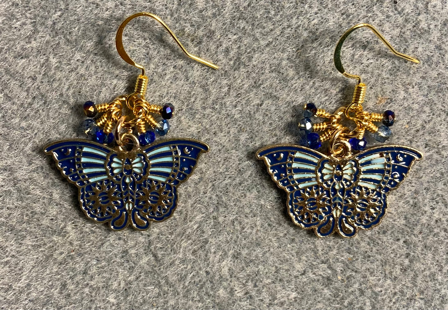 Dark blue and light blue enamel butterfly charm earrings adorned with tiny dangling dark blue and light blue Chinese crystal beads.