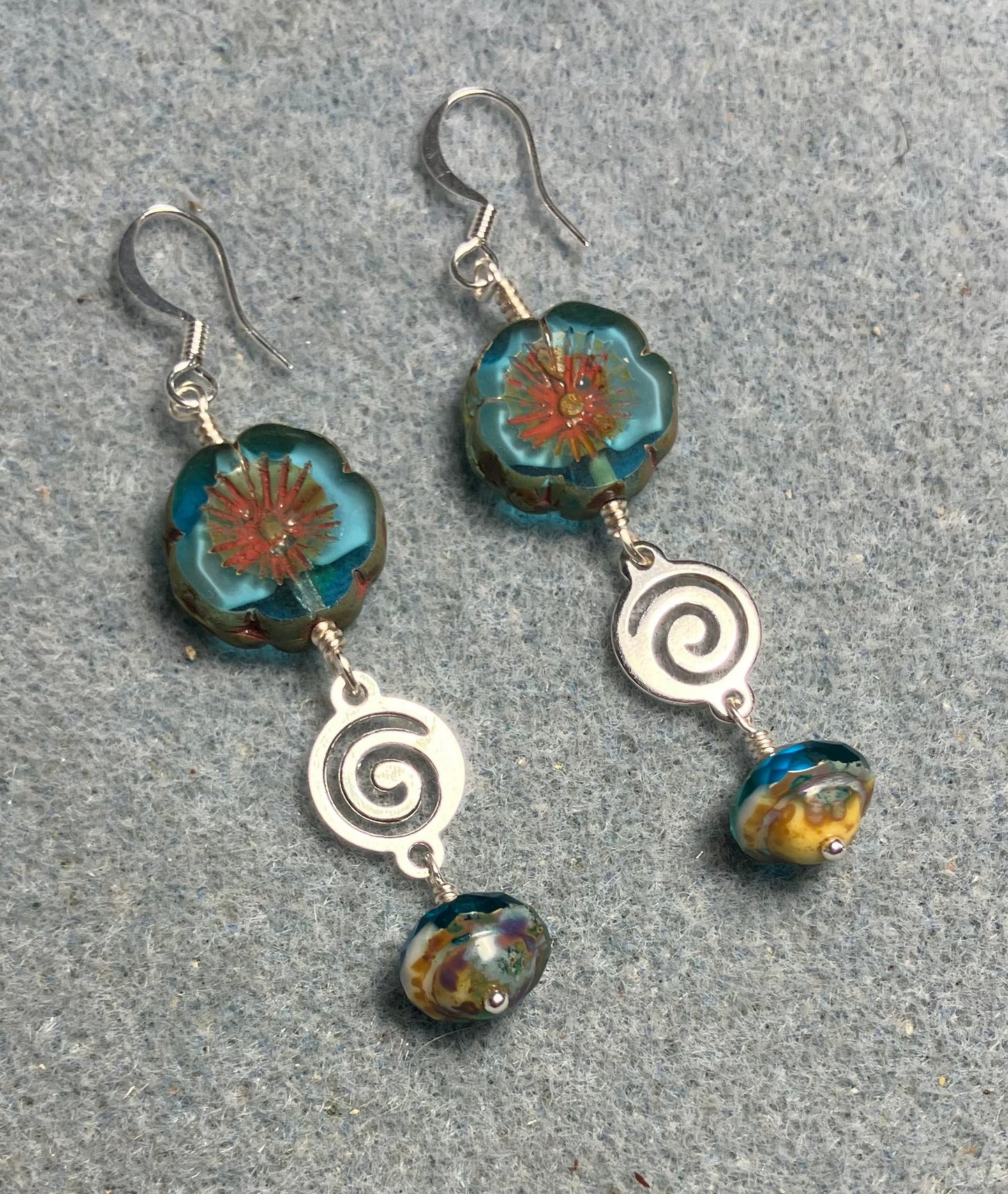 Turquoise and white Czech glass pansy bead earrings adorned with silver swirly connectors and turquoise Czech glass Saturn beads.
