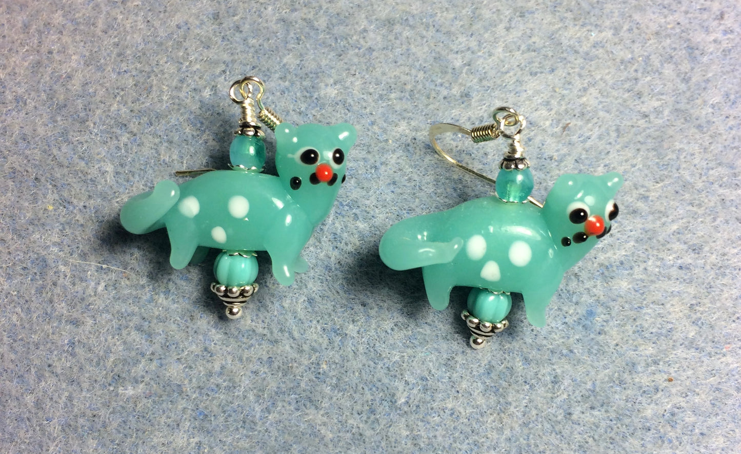 Opaque turquoise lamp work spotted cat bead earrings adorned with opaque turquoise Czech glass beads.