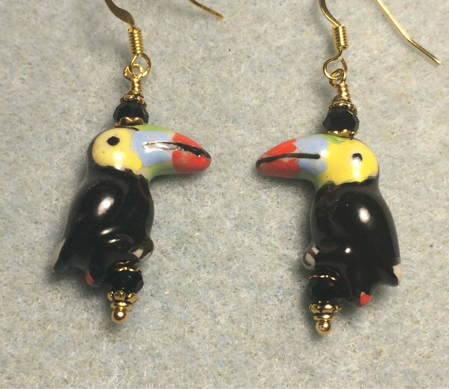 Black, yellow, blue, and red ceramic toucan bead earrings adorned with black Chinese crystal beads.