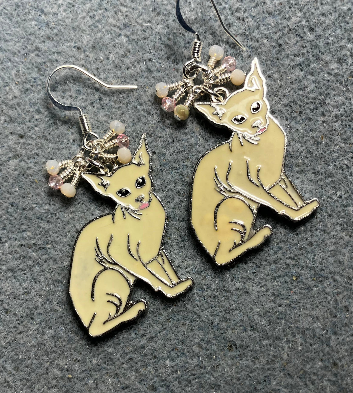 Off white and silver enamel Sphynx cat charm earrings adorned with tiny dangling white and pink Chinese crystal beads.