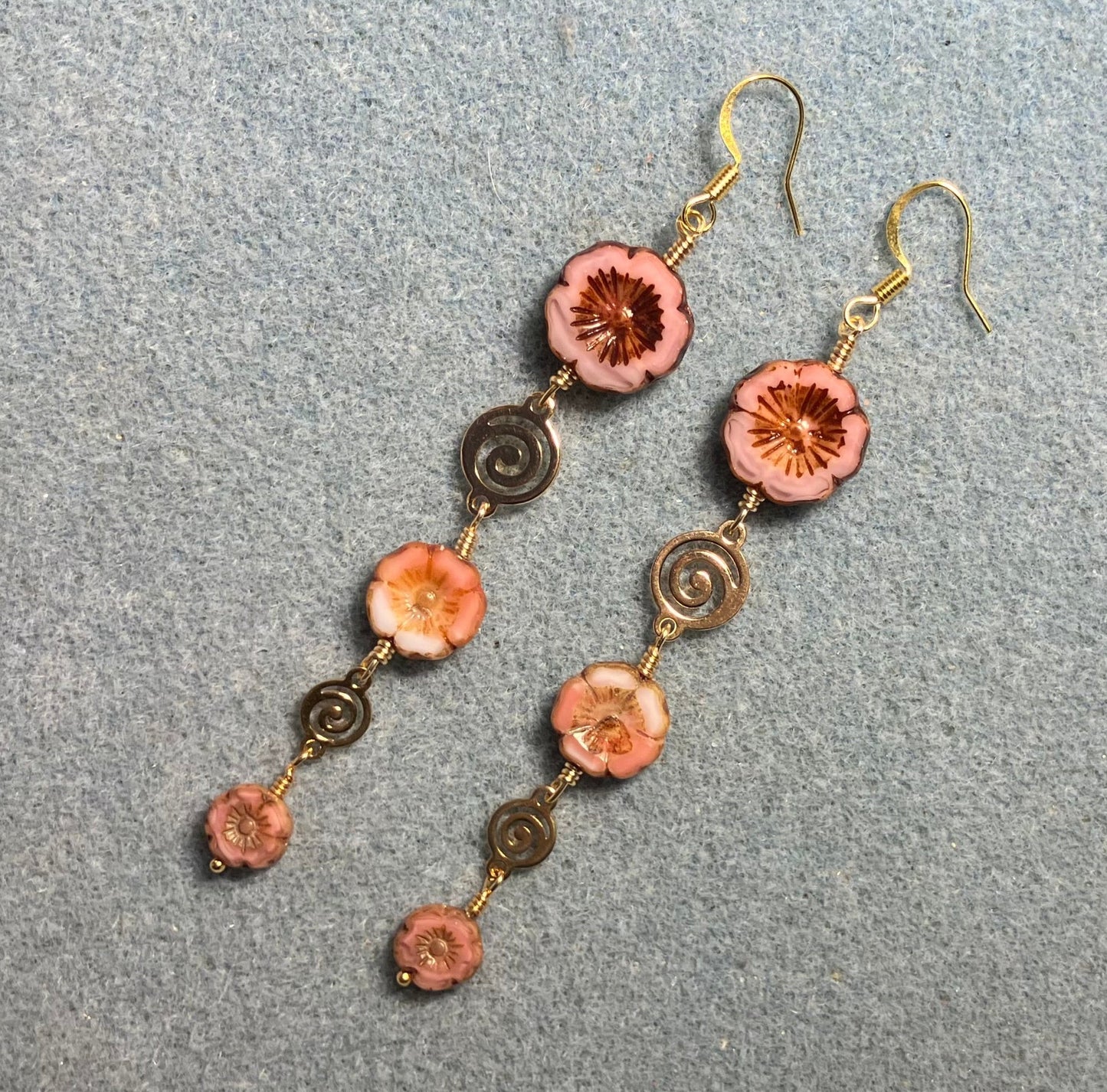 Extra long pink flower bead earrings made with three sizes of pink and white swirl Czech glass pansy beads joined by gold swirly connectors.